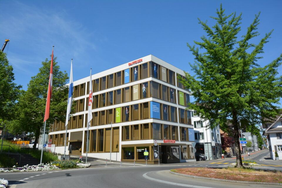 Bankgebäude mit Fahnen und Baum an einer Strassenecke