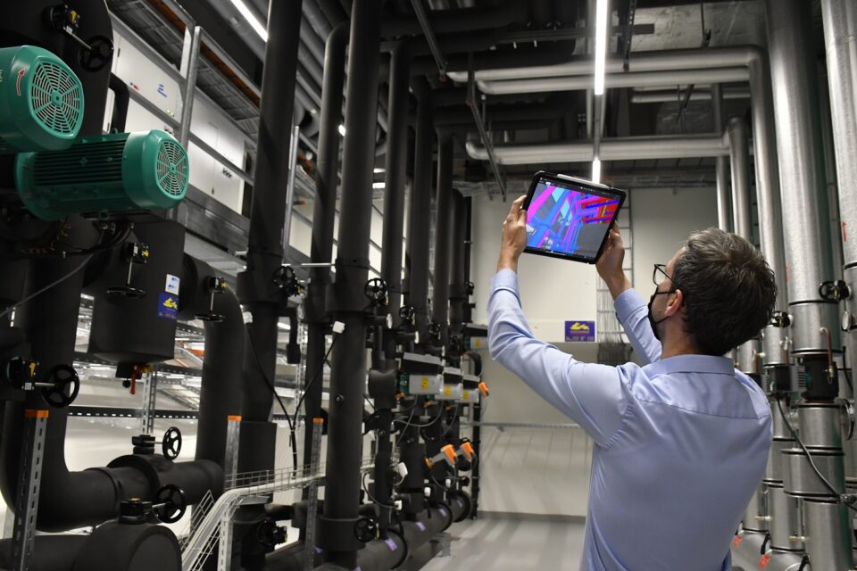 Ingenieur vergleicht das 3D-Modell auf dem Tablet mit der ausgeführten Installation