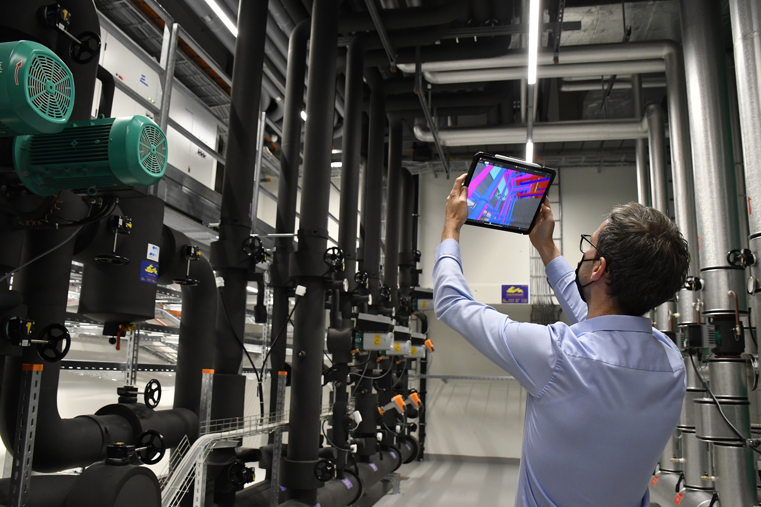 Ingenieur vergleicht das 3D-Modell auf dem Tablet mit der ausgeführten Installation