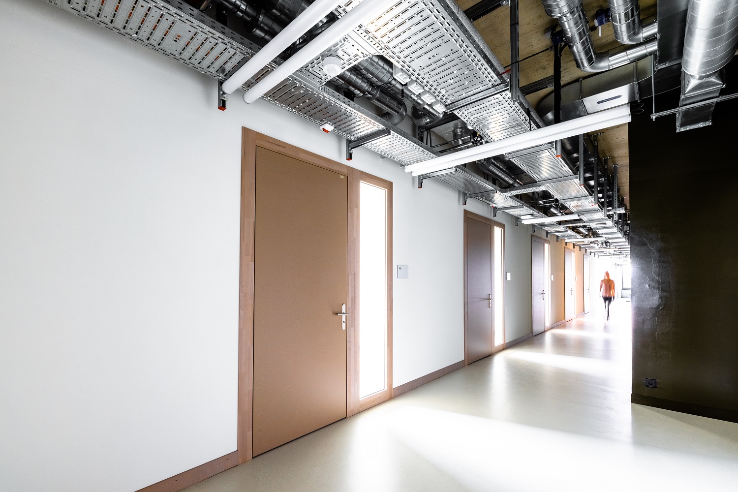 Korridor mit sichtbar an der Decke geführten Leitungen, Kanälen und Elektrotrassen