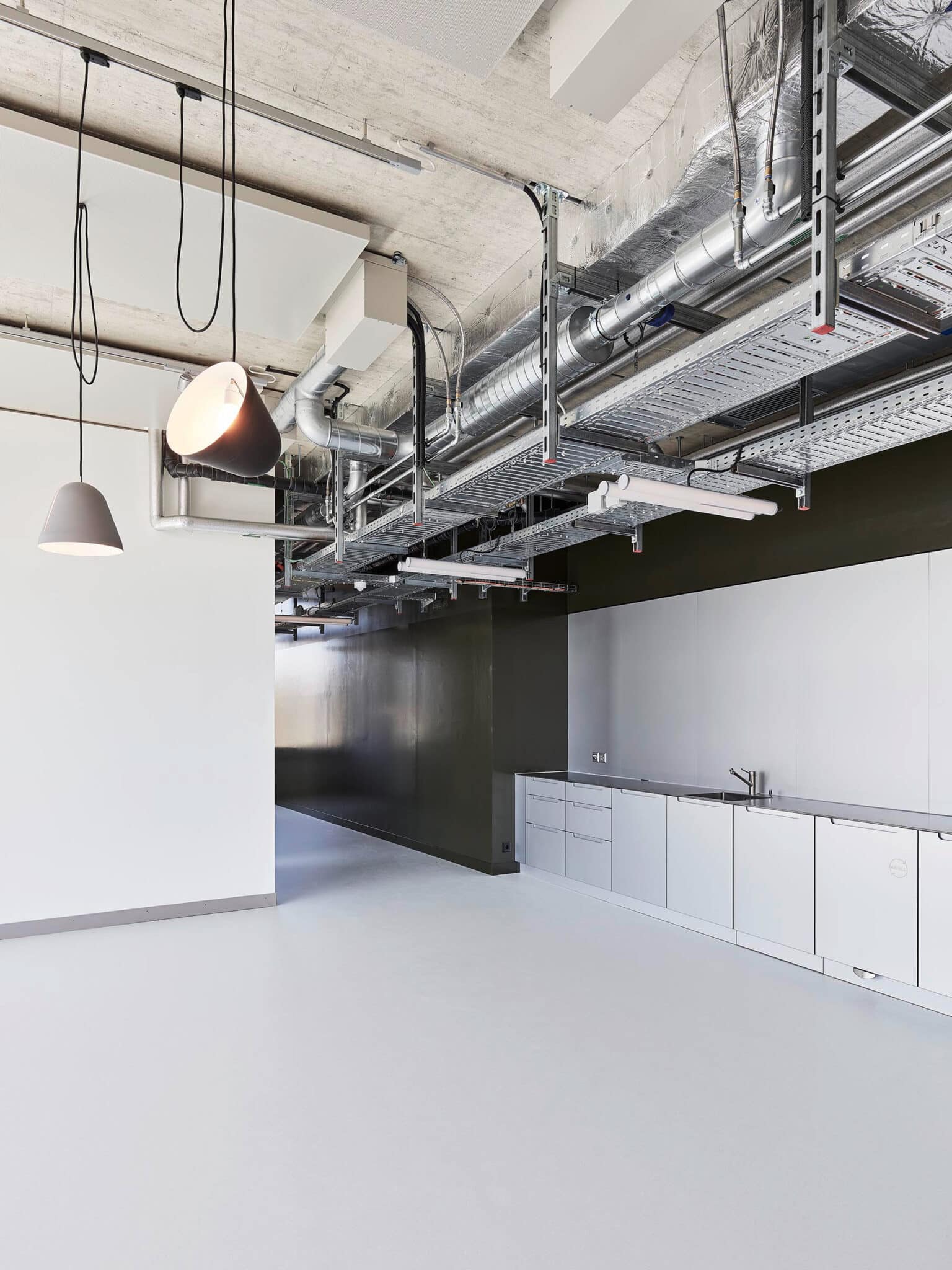 Laborraum mit offen an der Betondecke geführten Lüftungskanälen, Rohren und Kabeltrassen