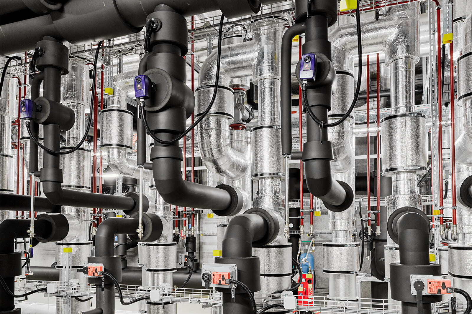 Schwarz gedämmte Rohrleitungen mit Regelventilen und elektrischen Stellantrieben