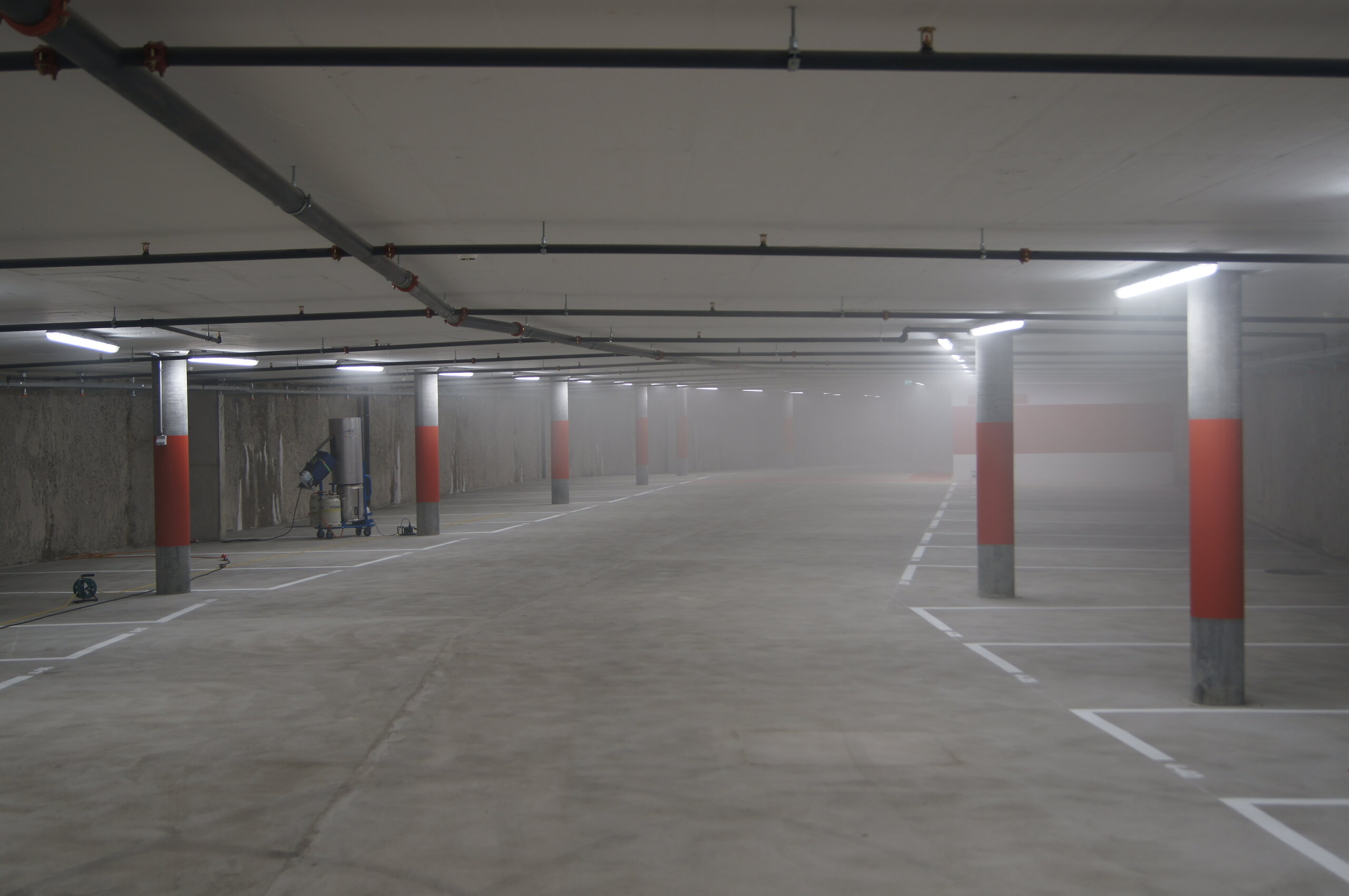Einstellhalle mit Sprinklerleitungen an der Decke und einem Rauchgenerator während eines Brandfalltests